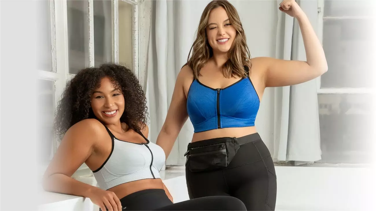 Two women wearing Parfait Lingerie sports bras, one in white leaning against a window and the other in blue flexing her arm.