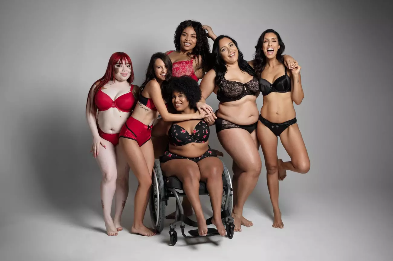 Diverse group of six women in lingerie posing together, celebrating body positivity and inclusivity in a studio setting.