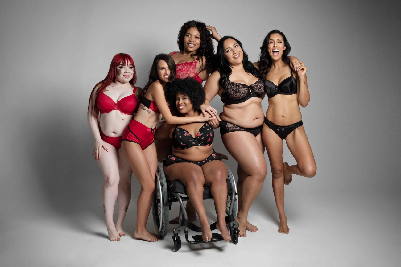 Diverse group of six women in lingerie posing together, celebrating body positivity and inclusivity in a studio setting.